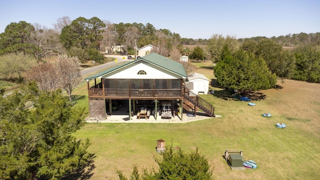 rear view of house featuring a deck, a patio, stairway, a yard, and a sunroom