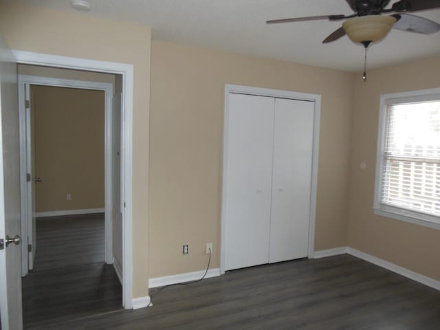 unfurnished bedroom featuring dark wood-type flooring, a closet, and ceiling fan