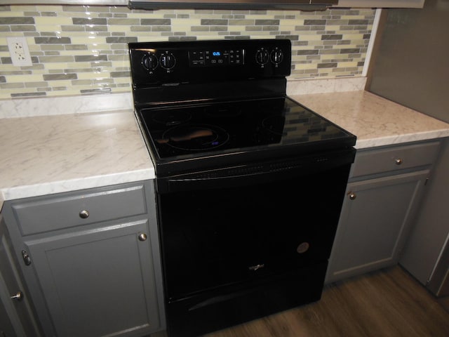 kitchen with gray cabinets, electric range, dark hardwood / wood-style floors, and backsplash