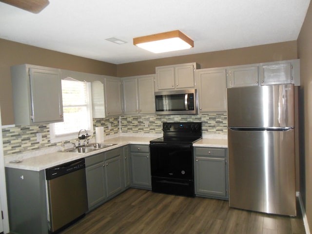 kitchen featuring decorative backsplash, dark hardwood / wood-style flooring, appliances with stainless steel finishes, gray cabinets, and sink