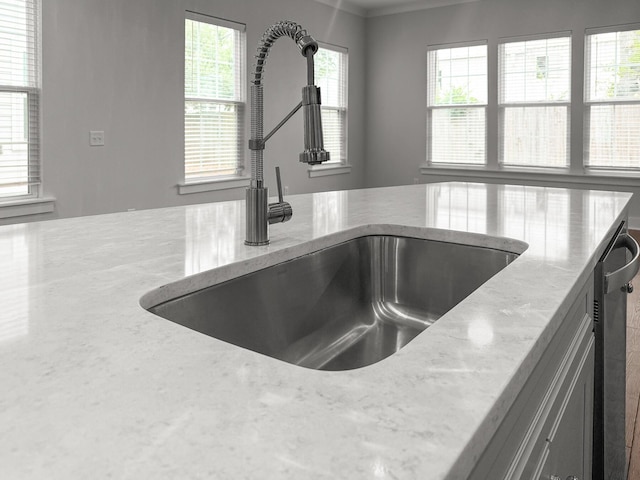 kitchen view of a sink, light stone countertops, and dishwasher
