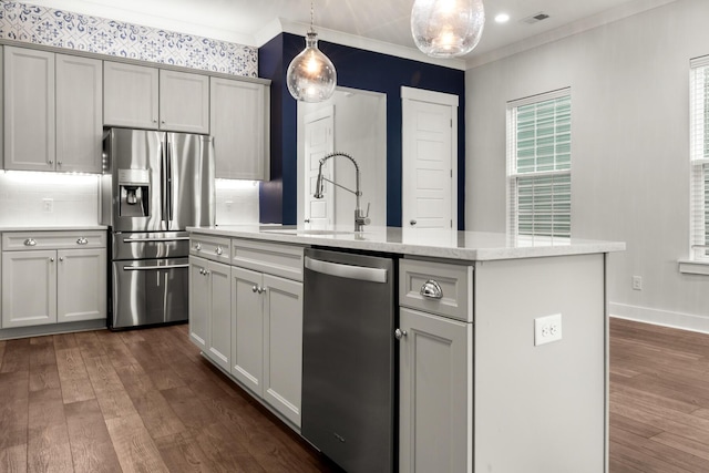 kitchen featuring appliances with stainless steel finishes, a sink, dark wood-style flooring, ornamental molding, and decorative light fixtures