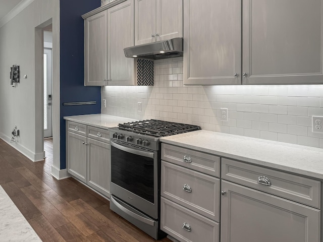 kitchen featuring gas range, under cabinet range hood, dark wood finished floors, baseboards, and decorative backsplash