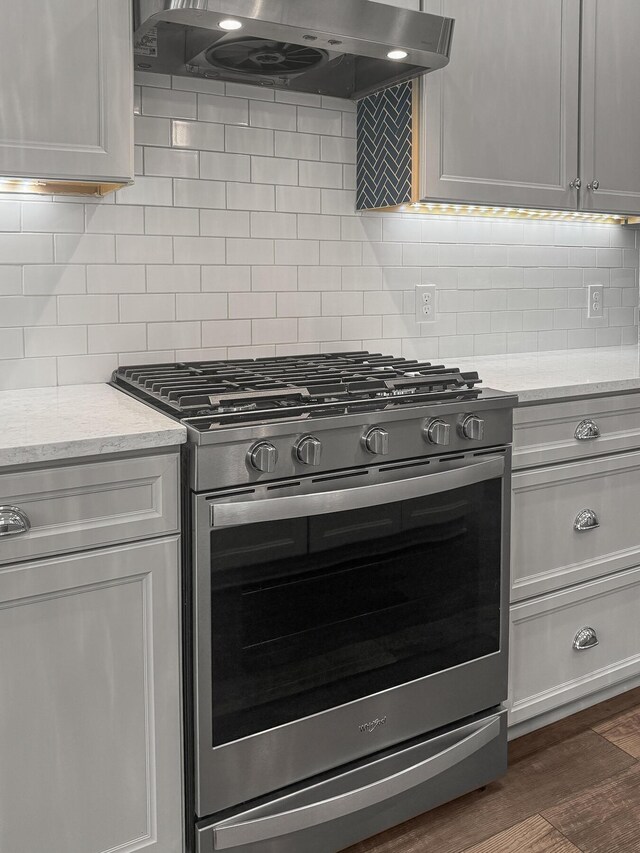kitchen with gas range, exhaust hood, decorative backsplash, and dark wood-type flooring