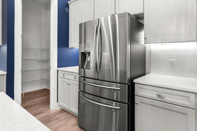 kitchen with stainless steel refrigerator with ice dispenser, light wood-style flooring, and tasteful backsplash