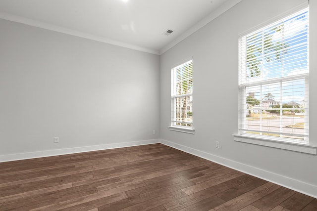 spare room featuring dark wood-type flooring, ornamental molding, and baseboards