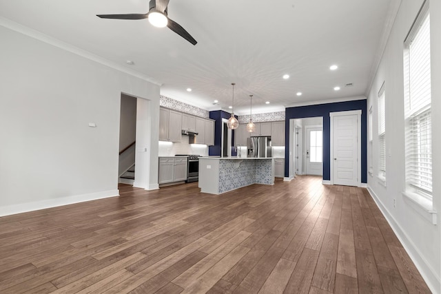 unfurnished living room featuring crown molding, ceiling fan, recessed lighting, dark wood-style flooring, and stairs