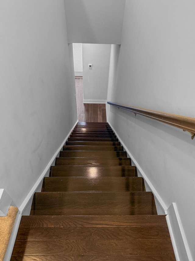 stairway with wood finished floors and baseboards