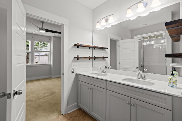 bathroom with a stall shower, double vanity, baseboards, and ceiling fan