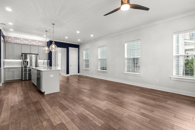 kitchen with appliances with stainless steel finishes, a sink, gray cabinetry, light countertops, and open floor plan