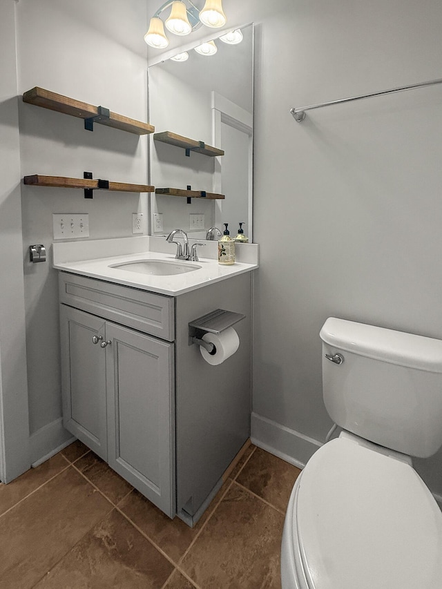 half bathroom with toilet, baseboards, vanity, and tile patterned floors