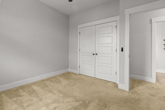 unfurnished bedroom featuring carpet, baseboards, a closet, and ceiling fan