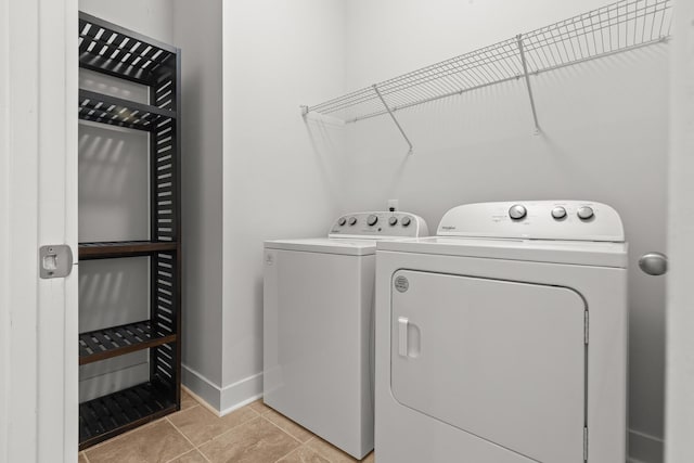 clothes washing area featuring washing machine and clothes dryer, baseboards, and light tile patterned floors