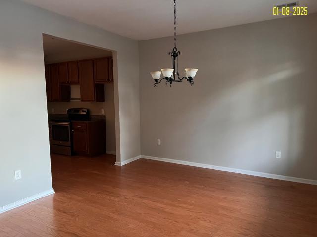 spare room with a chandelier and hardwood / wood-style flooring