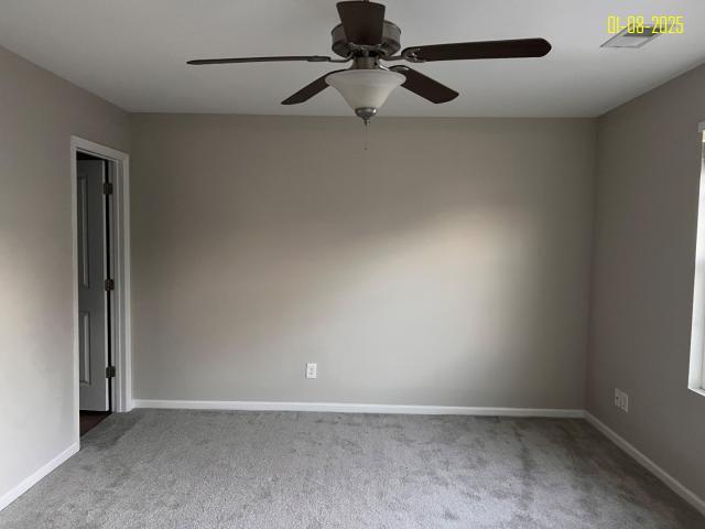 carpeted spare room featuring ceiling fan