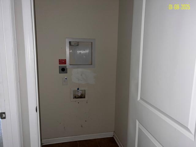 clothes washing area featuring hookup for an electric dryer, dark tile patterned flooring, and washer hookup