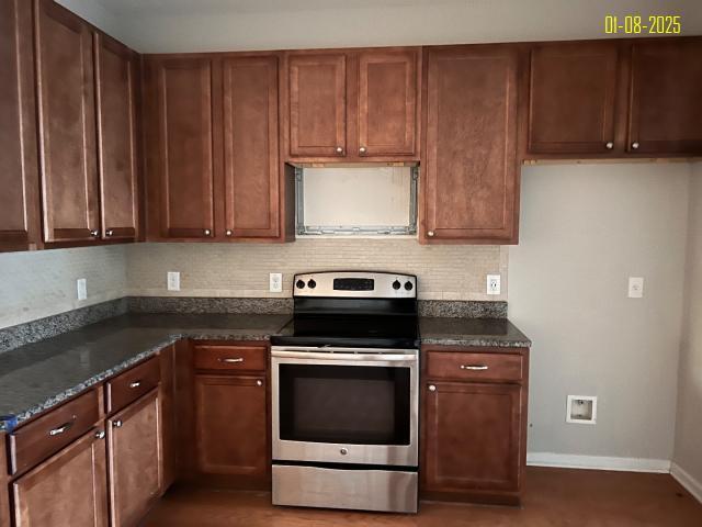 kitchen featuring electric stove and dark stone counters