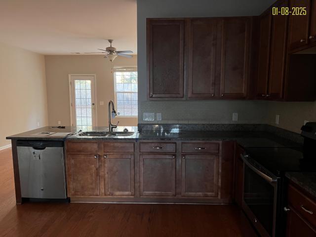 kitchen featuring ceiling fan, sink, stainless steel appliances, dark wood-type flooring, and kitchen peninsula