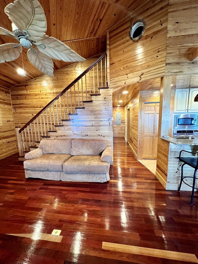 living room with wood walls, ceiling fan, wooden ceiling, high vaulted ceiling, and wood-type flooring