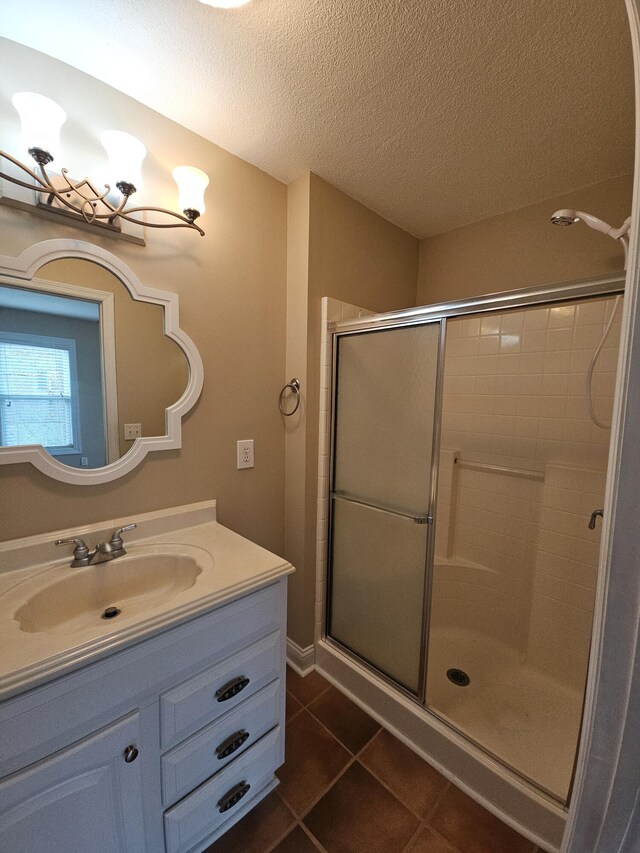 bathroom with vanity, a shower stall, a textured ceiling, and tile patterned floors