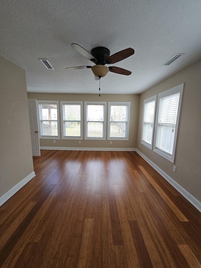 unfurnished room featuring dark wood-style floors, visible vents, and baseboards