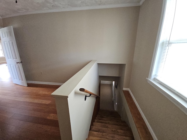 stairway with crown molding, wood finished floors, and baseboards