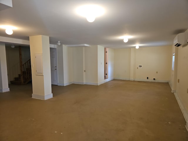 finished basement featuring baseboards, stairway, and a wall mounted AC