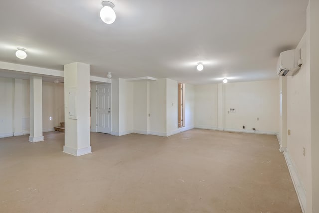 finished basement featuring a wall unit AC, baseboards, and stairs