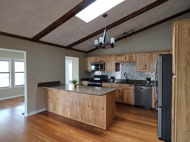 kitchen with dark countertops, vaulted ceiling with beams, a peninsula, stainless steel appliances, and a sink