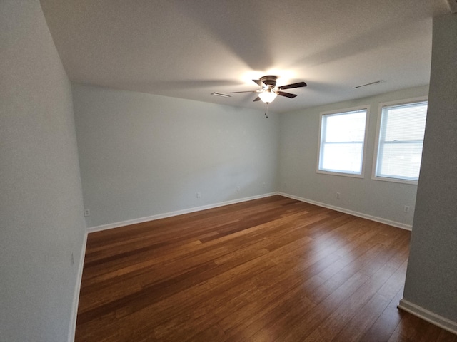 spare room with visible vents, dark wood finished floors, baseboards, and ceiling fan