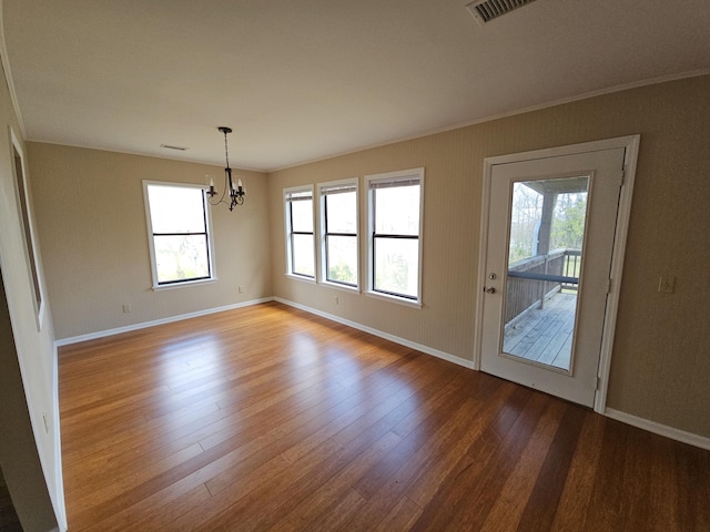 interior space featuring baseboards, visible vents, an inviting chandelier, and wood finished floors