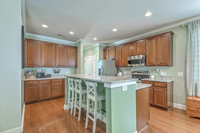 1408 Bimini Dr, Charleston, SC 29414 - kitchen featuring stainless steel appliances, light wood-type flooring, a kitchen island with sink, crown molding, and light stone counters