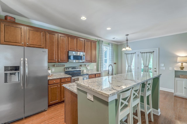 1408 Bimini Dr, Charleston, SC 29414 - kitchen featuring stainless steel appliances, ornamental molding, an island with sink, light stone counters, and brown cabinetry