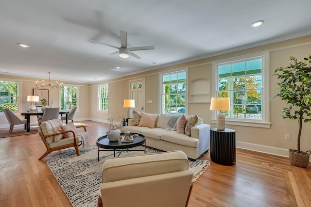 living room featuring light wood-type flooring, ceiling fan with notable chandelier, and ornamental molding