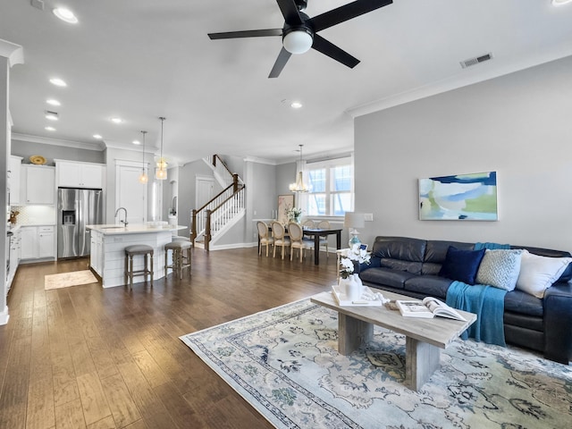 living room featuring sink, ornamental molding, dark hardwood / wood-style flooring, and ceiling fan with notable chandelier