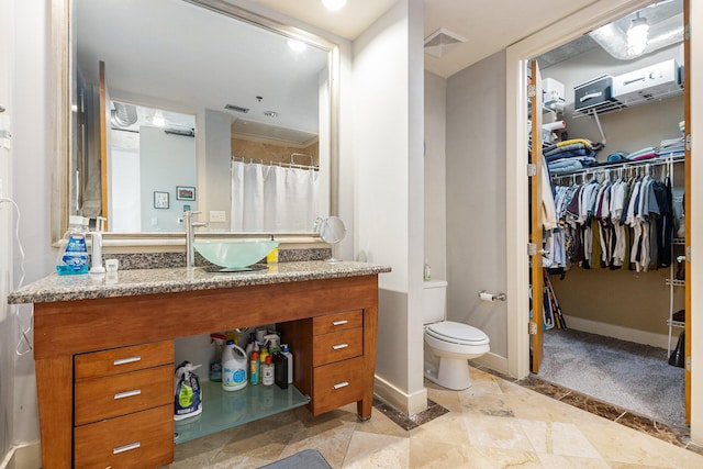 bathroom with visible vents, toilet, a spacious closet, and baseboards