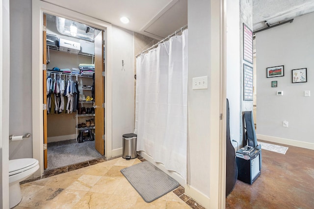 bathroom with a spacious closet, curtained shower, toilet, and baseboards