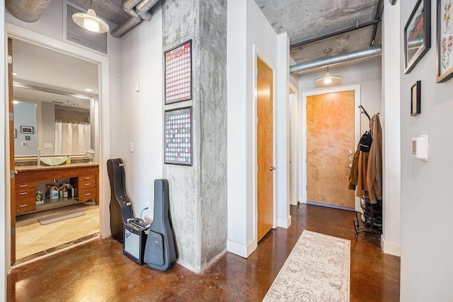 hallway featuring visible vents, concrete floors, and baseboards