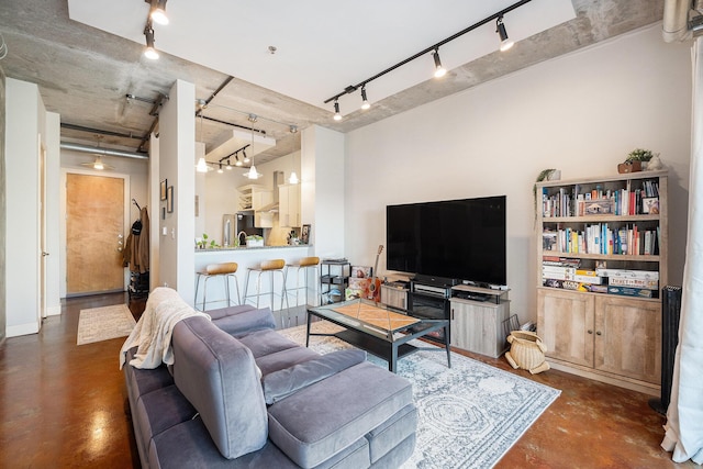 living room featuring rail lighting and finished concrete floors