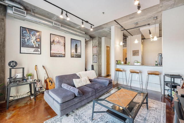 living area with concrete floors, rail lighting, and visible vents