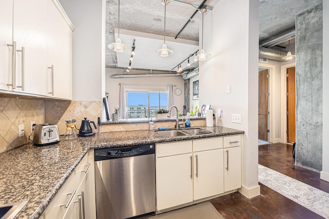 kitchen with rail lighting, backsplash, a sink, dark stone countertops, and dishwasher