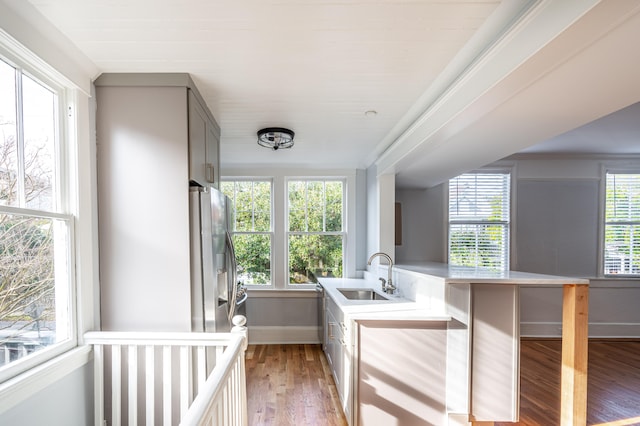 interior space with a breakfast bar, sink, kitchen peninsula, light hardwood / wood-style flooring, and stainless steel fridge