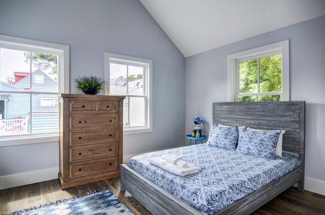 bedroom with multiple windows, lofted ceiling, and dark wood-type flooring