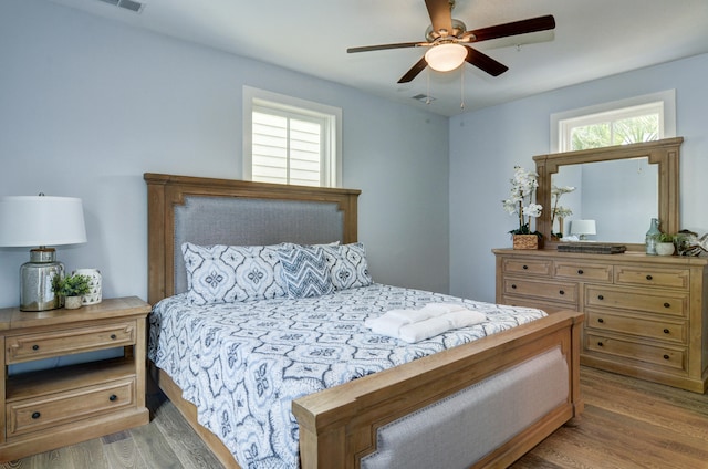 bedroom featuring multiple windows, wood-type flooring, and ceiling fan