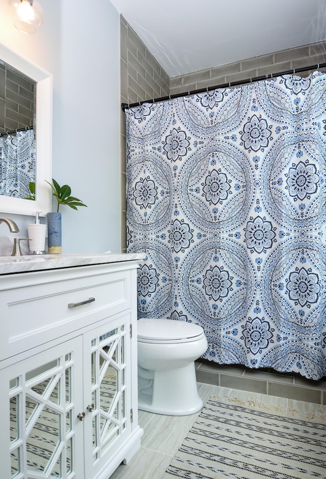 bathroom with curtained shower, tile patterned flooring, vanity, and toilet