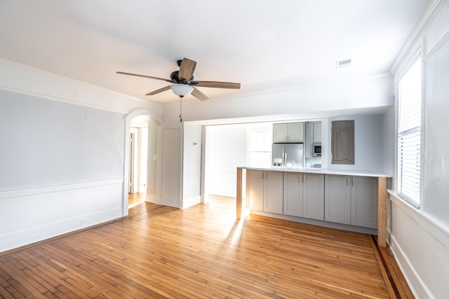 unfurnished living room featuring light hardwood / wood-style floors, ornamental molding, and ceiling fan