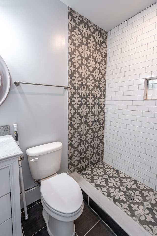 bathroom featuring a tile shower, tile patterned floors, vanity, and toilet