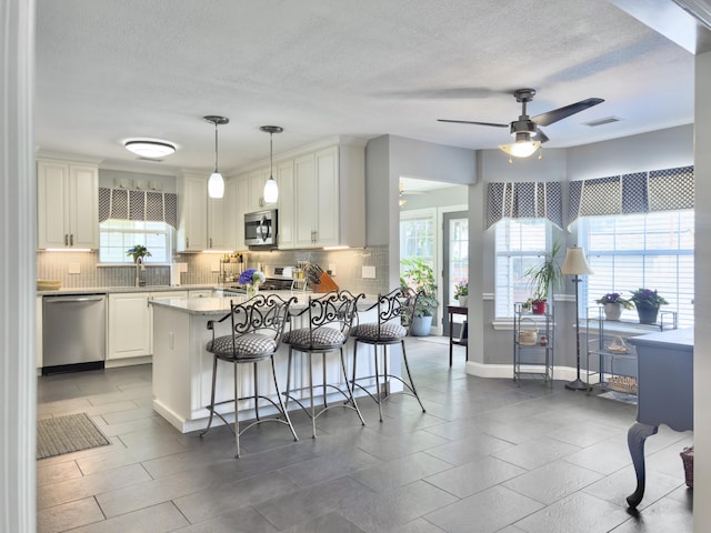 482 Planters Trace Dr, Charleston, SC 29412 - kitchen with stainless steel appliances, backsplash, a ceiling fan, a peninsula, and a kitchen breakfast bar