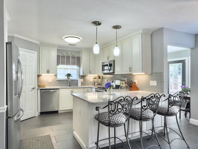 482 Planters Trace Dr, Charleston, SC 29412 - kitchen featuring appliances with stainless steel finishes, a peninsula, a sink, backsplash, and white cabinetry
