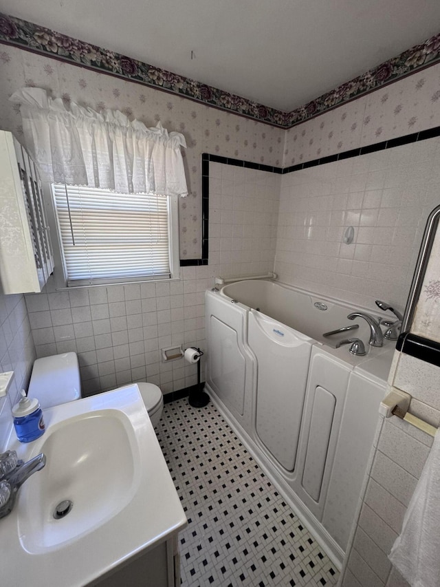 686 W Pine St, Varnville, SC 29944 - bathroom featuring tile walls, a bath, toilet, vanity, and tile patterned floors